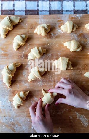 Frau rollt Croissant Teig auf Schneidebrett Stockfoto