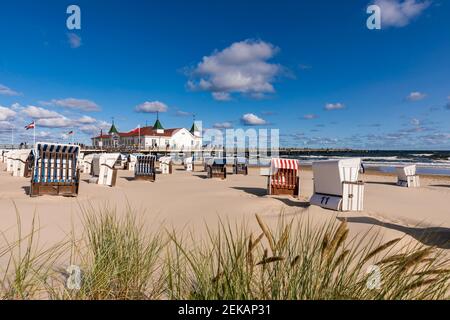 Deutschland, Mecklenburg-Vorpommern, Heringsdorf, Kapuzenliegen am leeren Strand mit Ahlbeck Pier im Hintergrund Stockfoto