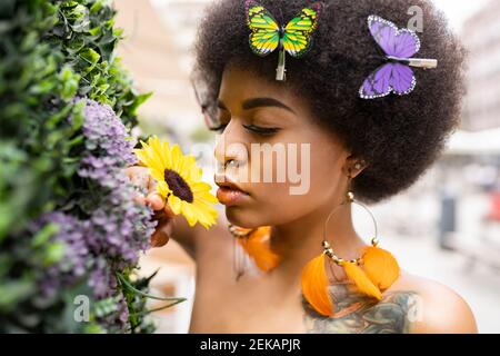 Junge Afro-Frau riecht Blume im Freien Stockfoto