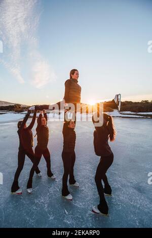 Weibliche Eiskunstläuferinnen üben auf gefrorenem See bei Sonnenuntergang Stockfoto