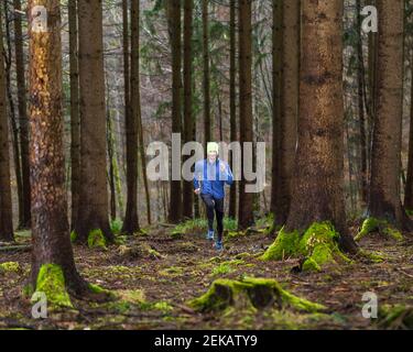 Junger Mann in blauer Jacke beim Joggen im Wald Stockfoto
