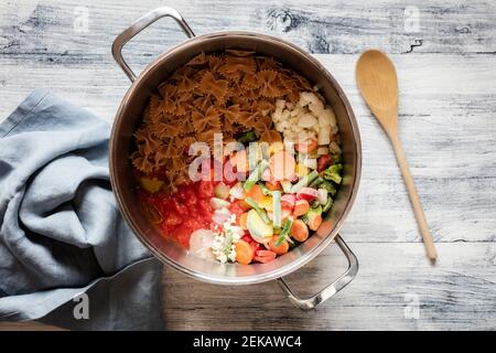 Kochtopf mit Rohzutaten für vegane Pasta mit Gemüse Stockfoto