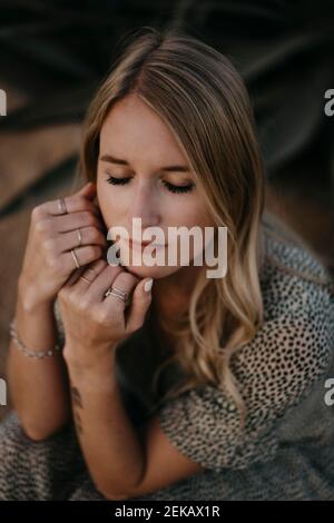 Blonde Frau mit geschlossenen Augen während des Sonnenuntergangs Stockfoto