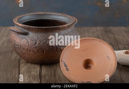 Uralter Topf mit einem Holzlöffel auf einem Holztisch Stockfoto