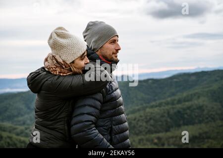 Das Touristenpaar schaut weg, während es am Aussichtspunkt gegen den Himmel steht Stockfoto