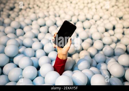Hand einer jungen Frau, die das Handy in der Kugelgrube hält Stockfoto