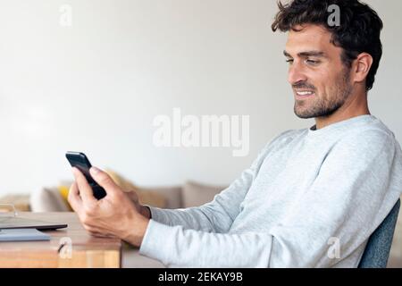 Mann mit Handy, während zu Hause sitzen Stockfoto