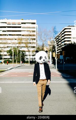 Geschäftsmann trägt Panda Maske zu Fuß auf dem Weg in der Stadt Stockfoto