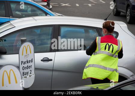 Maskierter mcdonalds-Arbeiter, der Essen zu den Autos lieferte, die zum Mitnehmen geparkt waren Order Bay während Coronavirus Einschränkungen Newtownabbey Nordirland Großbritannien Stockfoto