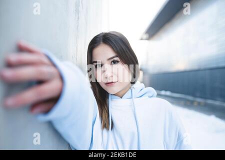 Frau streckt die Hand, während sie an der Wand steht Stockfoto