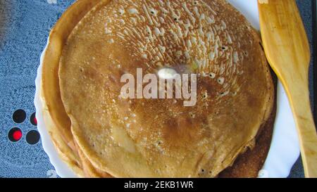 Russische Pfannkuchen sind gestapelt, ein Stück Butter schmilzt darüber. Frühlingsfest Maslenitsa. Stockfoto