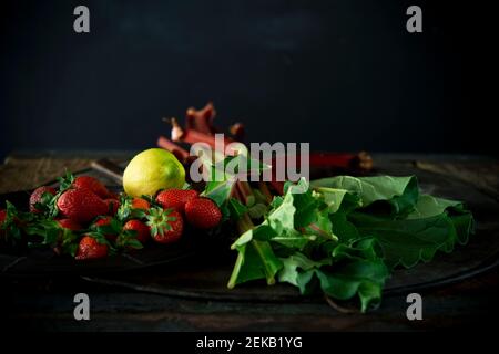 Studio Schuss von frischen Rhabarber Stiele, Erdbeeren und einzelne Zitrone Stockfoto