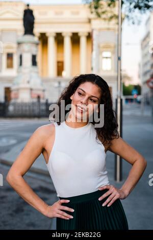 Lächelnd schöne Frau mit Armen Akimbo auf der Straße in Stadt Stockfoto