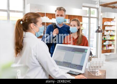 Weibliche Kassiererin mit Kunden in Schutzmaske in der Apotheke Kasse Stockfoto