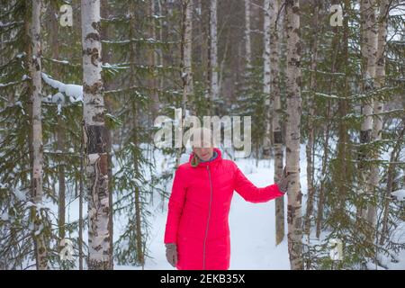 Frau in einem leuchtend rosa warme Jacke in einem Winter verschneiten Wald. Winter Natur des Nordens von Russland. Sport und Erholung. Stockfoto