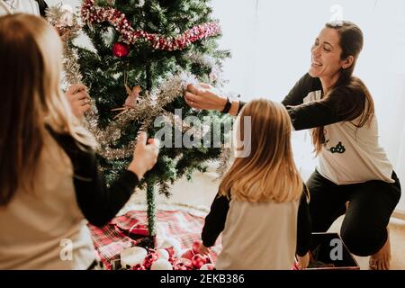 Bruder und Schwestern schmücken den Weihnachtsbaum zu Hause Stockfoto