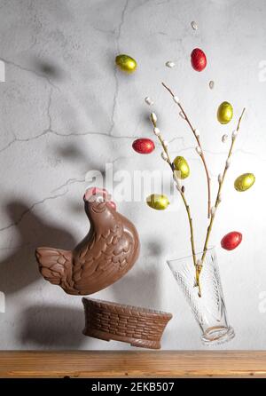 Weide in einer Vase, Schokoladeneier und ein Korb. Levitation, Konzept, Gratulation, Postkarte für Ostern. Hochwertige Fotos Stockfoto