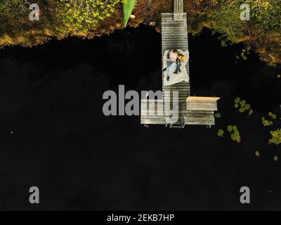 Luftaufnahme von Mutter und Tochter, die auf dem Pier sitzen see im Wald Stockfoto