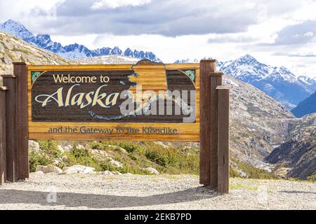 Willkommen in Alaska Zeichen Anfang Juni an der Kanada/USA Grenze neben dem Klondike Highway nordöstlich von Skagway, Alaska, USA Stockfoto