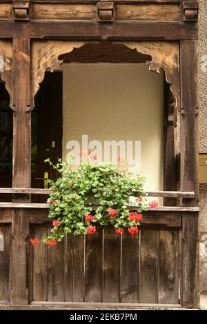 Fassade eines Hauses in Liechtenstein, mit einer wunderschön geschnitzten Holzveranda und dekorativen Blumen Stockfoto