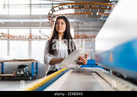 Weibliche Inspektor mit Datei wegschauen, während in der Industrie stehen Stockfoto