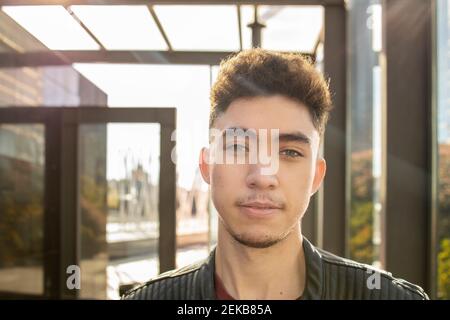 Ein junger Mann mit Sonnenbrille blickt weg, während er in der Lobby steht Stockfoto