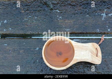 Handgemachte skandinavische Tasse mit Tee auf einer Bank, Foto auf der Straße. Hochwertige Fotos Stockfoto