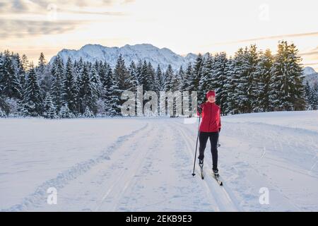 Ältere Frau in warmer Kleidung Skifahren auf Schnee über Berg Stockfoto