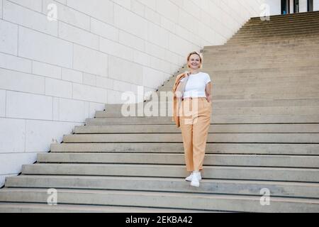 Reife Geschäftsfrau mit der Hand in der Tasche, die sich über die Treppe nach unten bewegt Stockfoto