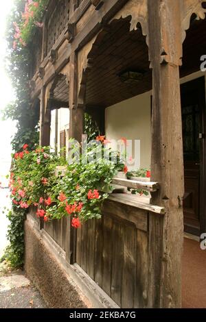 Fassade eines Hauses in Liechtenstein, mit einer wunderschön geschnitzten Holzveranda und dekorativen Blumen Stockfoto