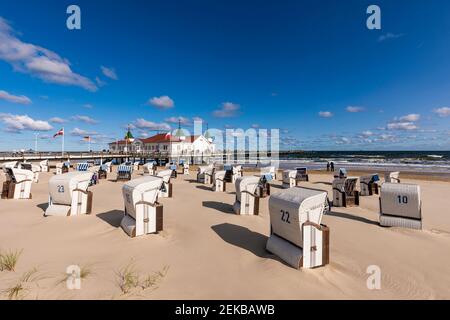 Deutschland, Mecklenburg-Vorpommern, Heringsdorf, Kapuzenliegen am leeren Strand mit Ahlbeck Pier im Hintergrund Stockfoto