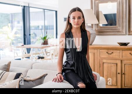 Stilvolle selbstbewusste Teenager-Mädchen trägt schwarze Oberseite auf dem Sofa sitzen Im Wohnzimmer Stockfoto