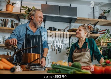 Männlicher Koch im Gespräch mit Kollegen beim Kochen in der Küche Stockfoto
