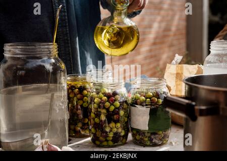 Senior Mann Gießen Olivenöl in Glas auf dem Tisch Stockfoto