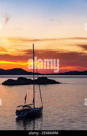 Golden, Sunset View mit festgedeckter Yacht auf ruhigen Gewässern von Sardinien über ruhige Mittelmeer zu Inseln von La Madallena und Caprera-Portrait View. Stockfoto