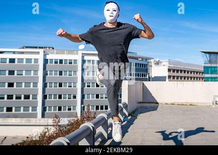 Mann trägt Maske läuft auf dem Dach während sonnigen Tag Stockfoto