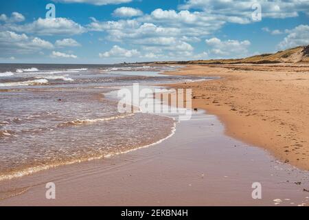 Wellen schlagen sich an einem Sandstrand am Nordufer von Prince Edward Island, Kanada, auf. Stockfoto