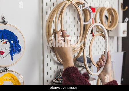 Hände der jungen Frau mit Stickereirahmen an der Wand hängen Im Studio Stockfoto