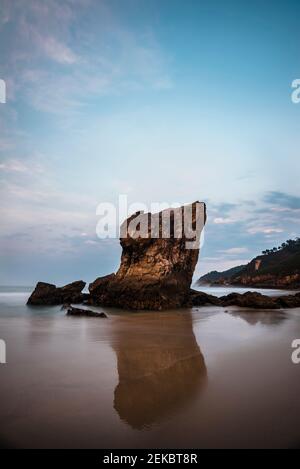 Rauer Küstenmeer-Stapel, der sich in nassem Strandsand in der Abenddämmerung widerspiegelt, Asturien, Spanien Stockfoto