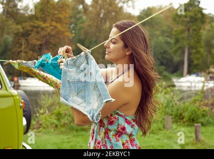 Junge Frau hängend Wäsche waschen auf Wäscheleine von Camper Van Stockfoto
