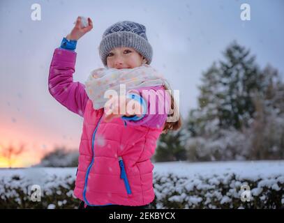 Verspieltes Mädchen Schneeball im Winter im Schnee werfen Stockfoto