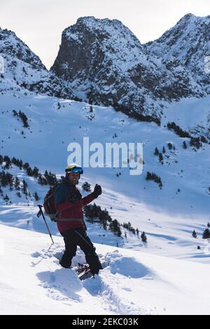 Glücklicher männlicher Skifahrer auf verschneiten Berg während Sonnenaufgang Stockfoto