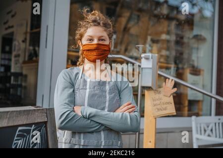 Junge Unternehmerin mit gekreuzten Armen gegen Einzelhandelsgeschäft Stockfoto