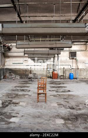 Leere Holzstühle in einer verlassenen Fabrik Stockfoto