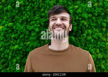 Glückliche männliche professionelle Blick weg vor grünem Hintergrund Stockfoto