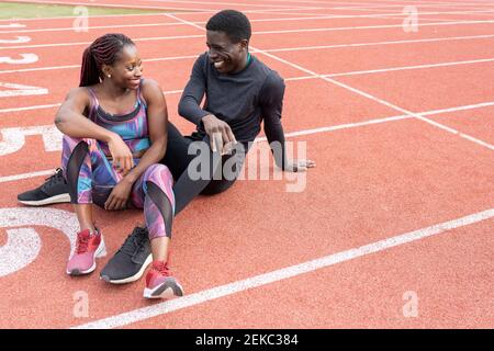 Männliche und weibliche Sportsperson lächeln, während sie einander anblicken Auf Laufstrecke Stockfoto