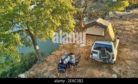 Luftaufnahme eines Paares, das mit ihrem Jeep und Dachzelt zeltete und am Flussufer, Cunene River Area, Angola frühstückte Stockfoto