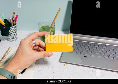 Frau mit Kreditkarte Online-Shopping über Laptop bezahlen Und gesunder grüner Saft im Hintergrund Stockfoto