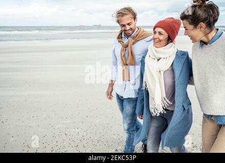 Gruppe von Freunden, die gemeinsam entlang des sandigen Küstenstrandes spazieren Stockfoto