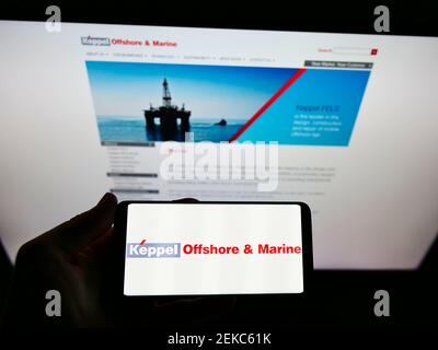 Person hält Smartphone mit Logo der singapurischen Firma Keppel Offshore und Marine auf dem Bildschirm vor der Website. Konzentrieren Sie sich auf die Telefonanzeige. Stockfoto